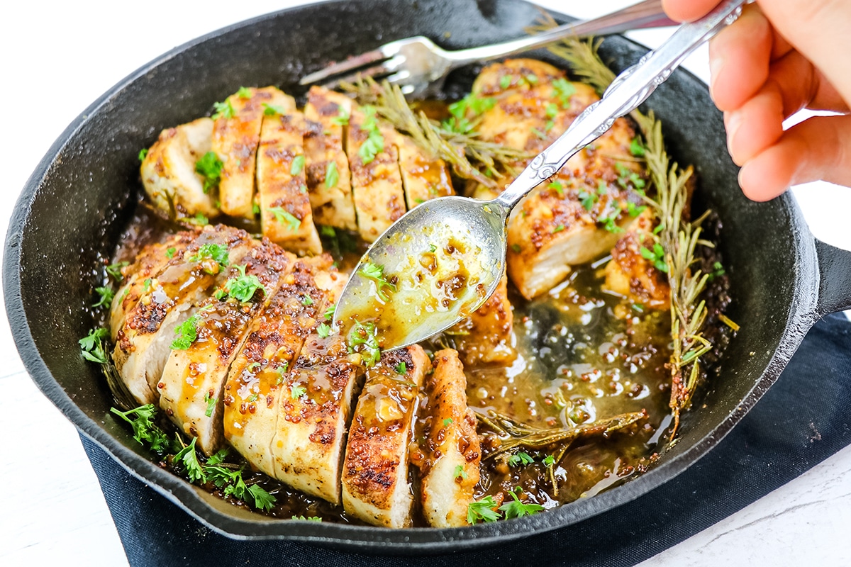 spoon pouring sauce over chicken