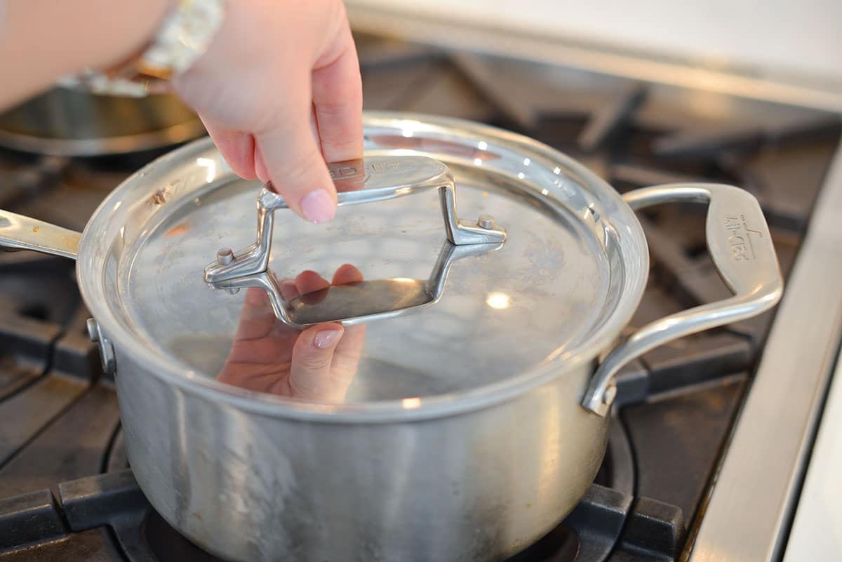 hand putting lid on a saucepan