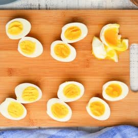 overhead of eggs cut in half on a wood cutting board