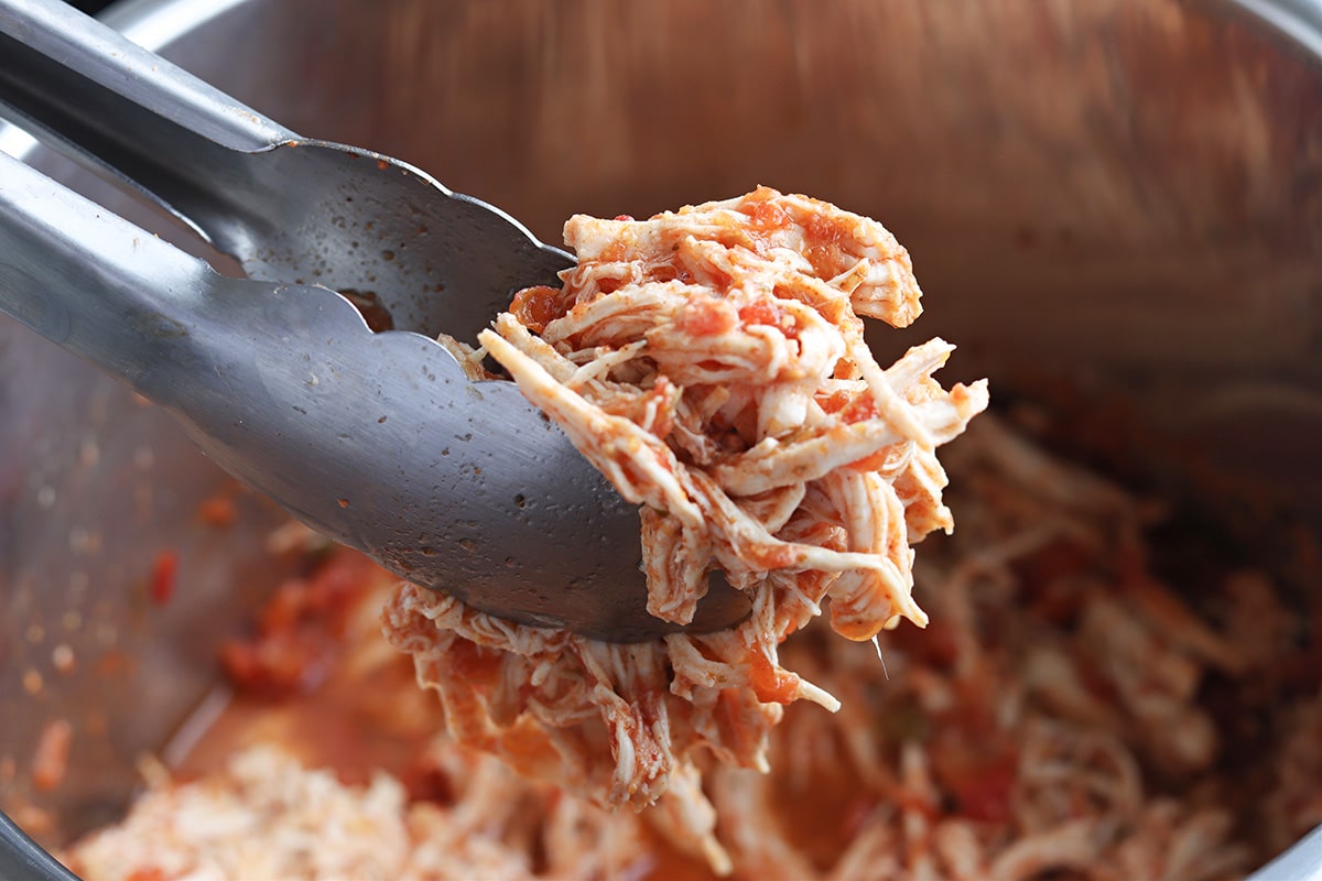 tongs holding shredded chicken