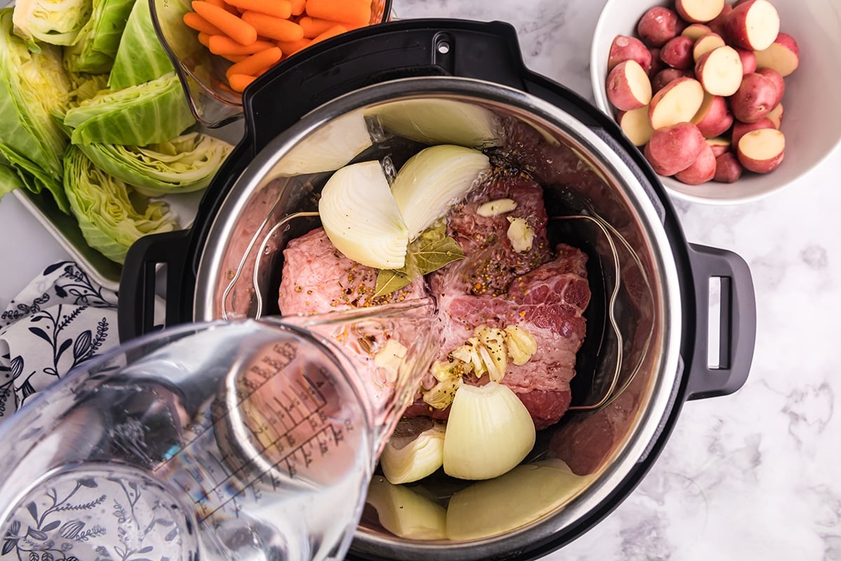 pouring water into the instant pot with a beef roast