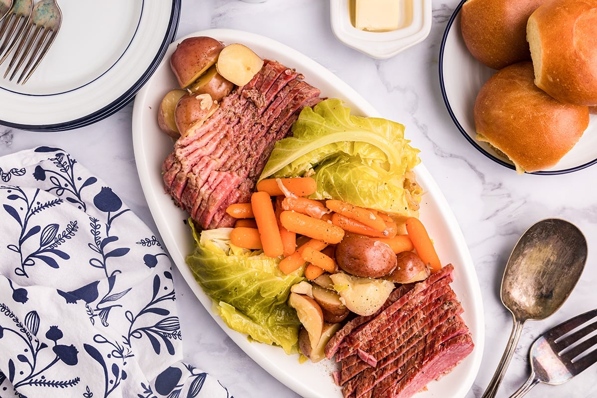 serving platter of sliced corned beef with carrots and cabbage