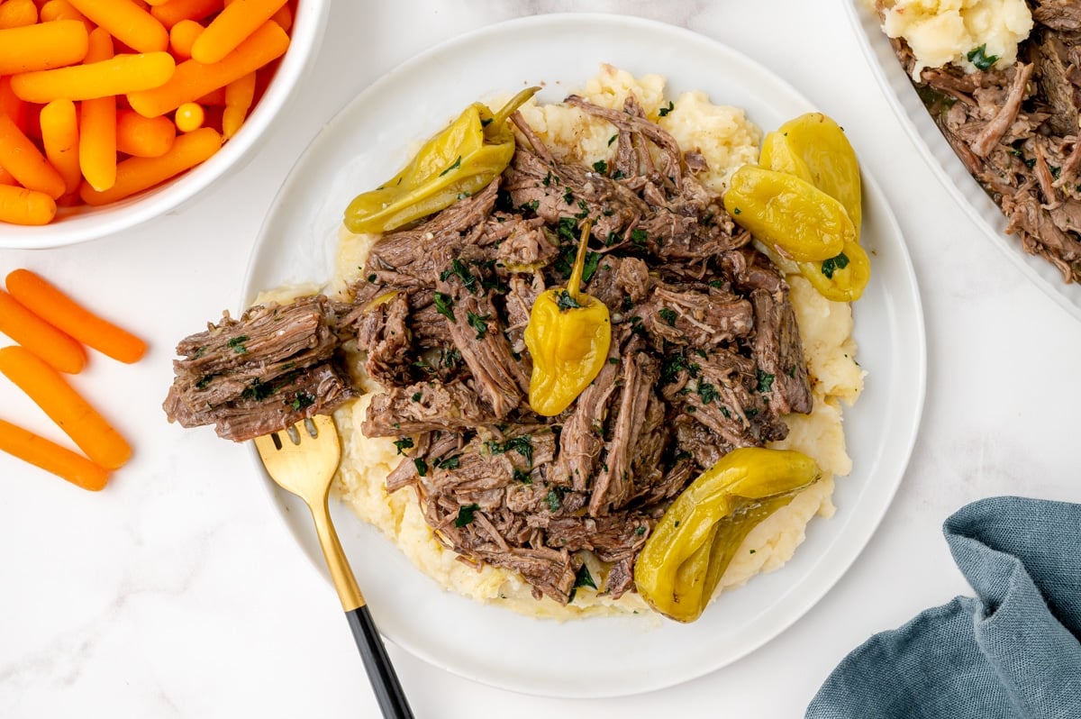 plate of pot roast over potatoes with a fork