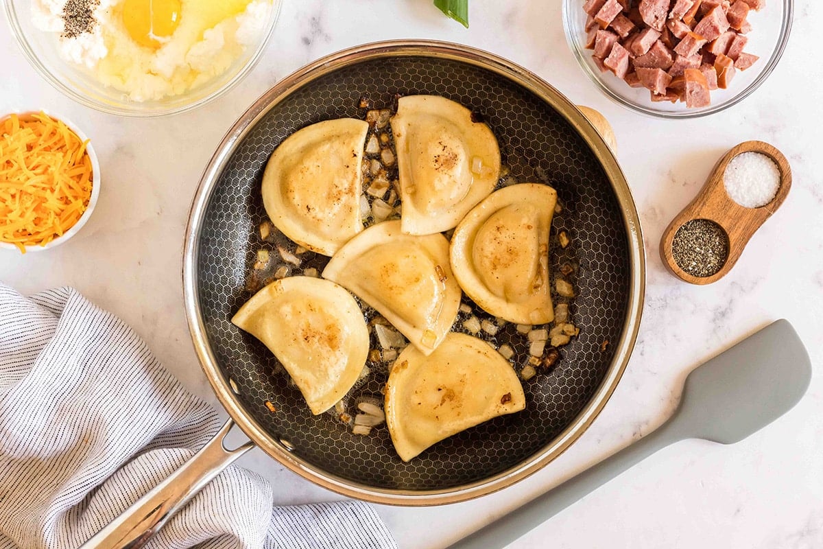 pierogies sautéing in pan with onion