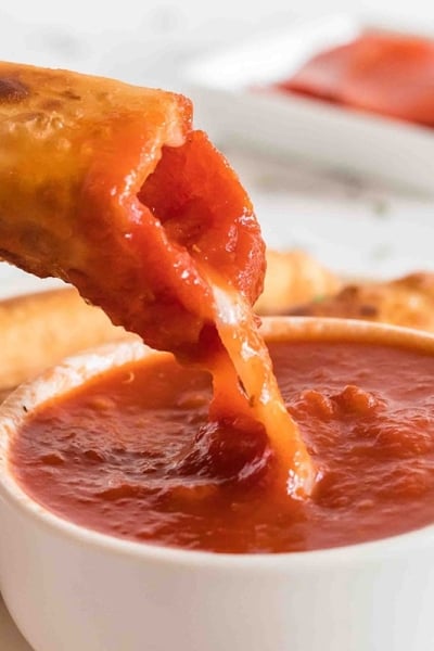 close up of pizza log dipped into sauce