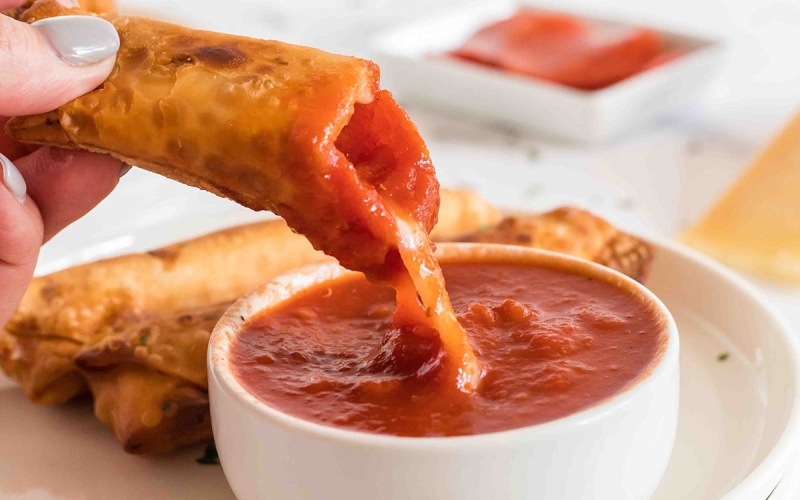 close up of pizza log dipped into sauce