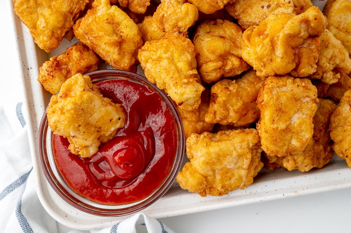 chicken dipped into bowl of ketchup