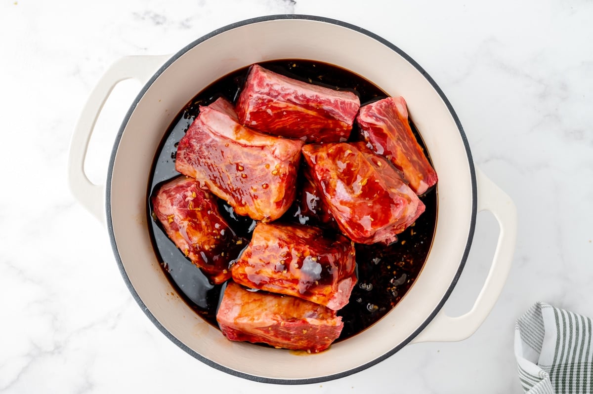 sauce poured over short ribs in a dutch oven