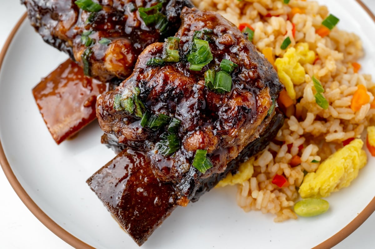 angled shot of short ribs on a plate with rice