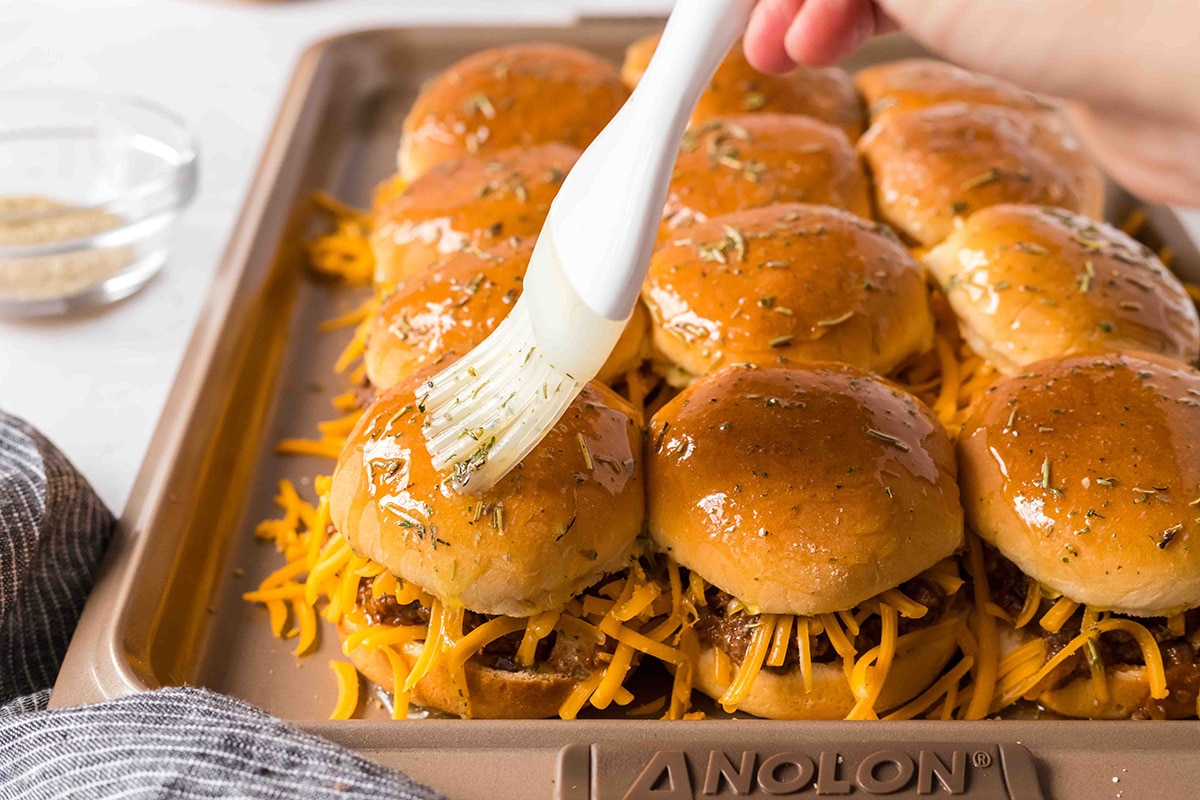 hand brushing butter onto sliders