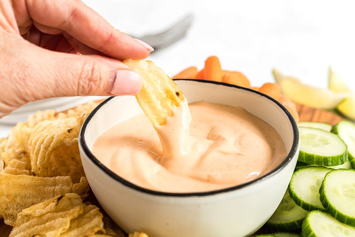 chip dipping into bowl of spicy aioli