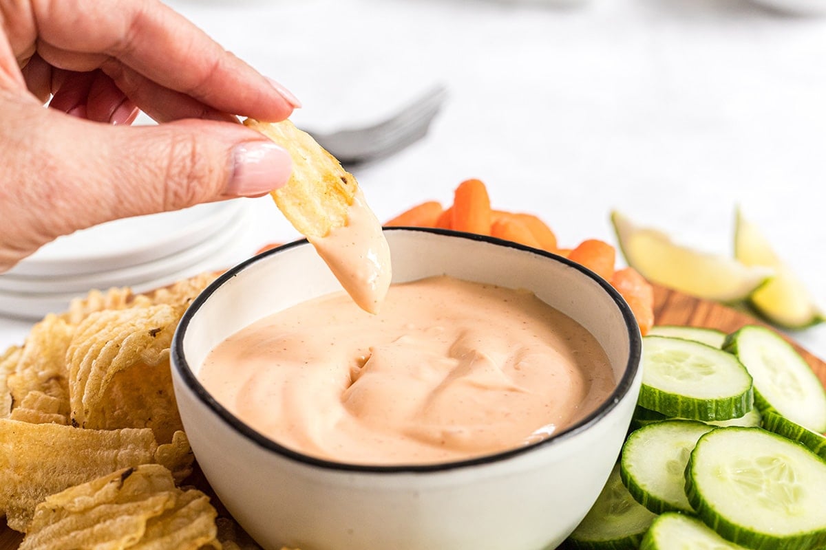 chip dipping into bowl of sriracha aioli