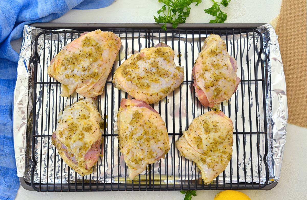 overhead shot of seasoned raw chicken thighs on a baking sheet