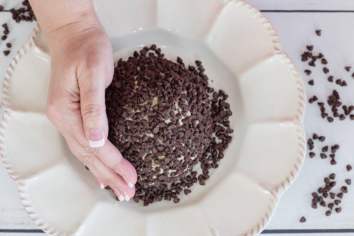 hand pressing chocolate chips into cheese ball