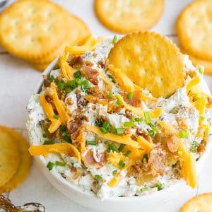 cracker in bowl of cheesy bacon dip