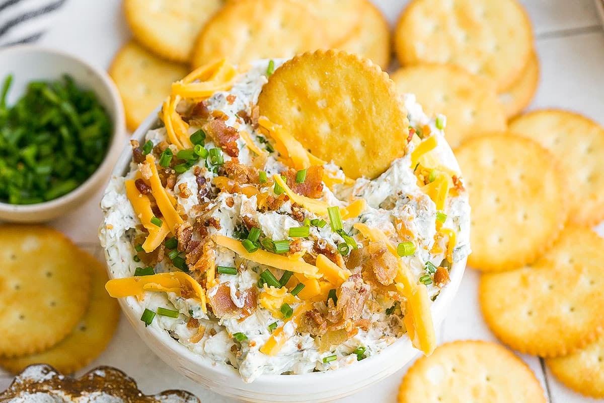 close up angled shot of crack dip in a bowl with a cracker