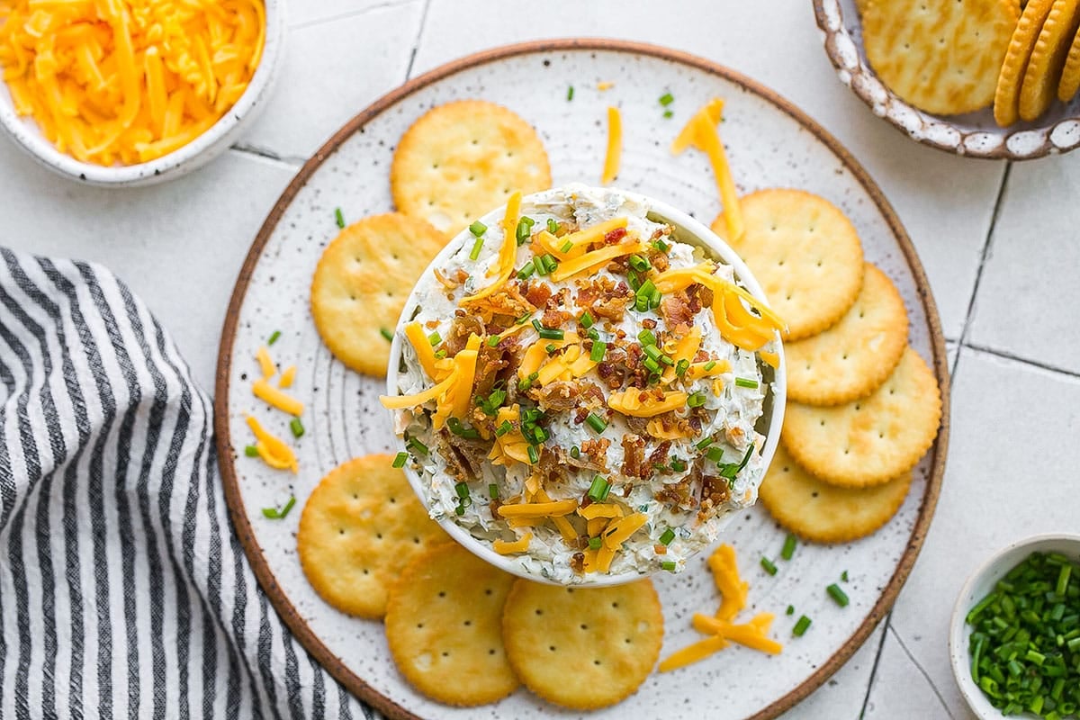 overhead shot of crack dip with bacon in a bowl surrounded by crackers