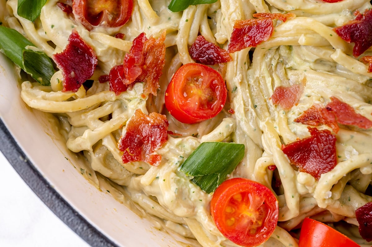 close up of tomatoes and bacon topping pasta