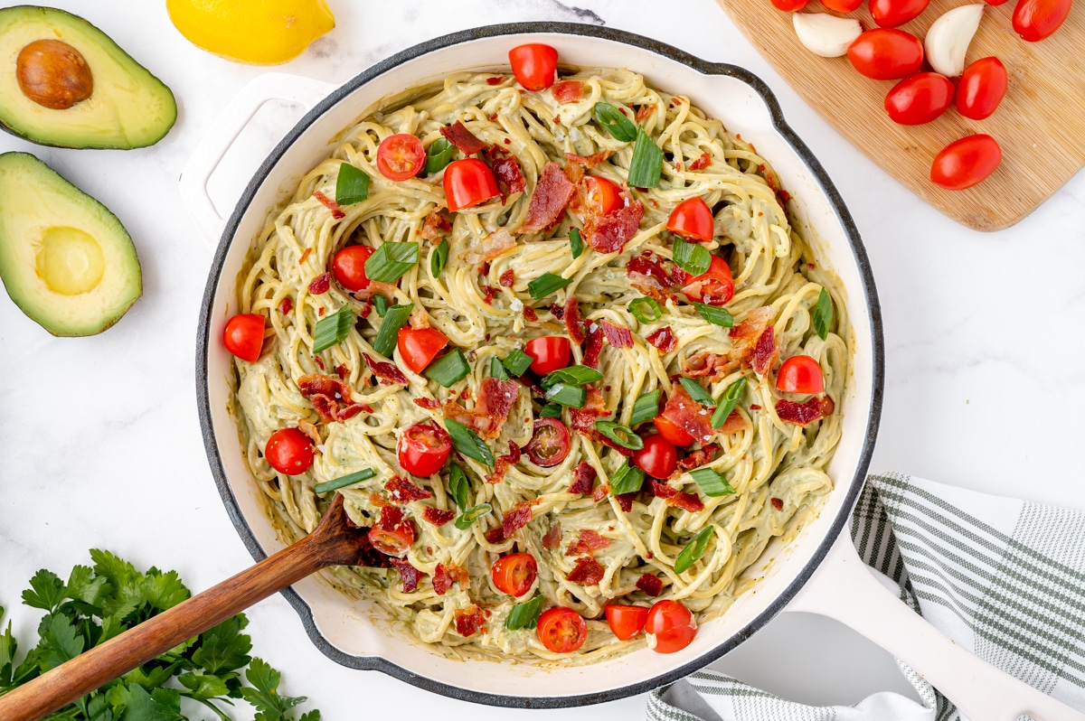 pan of creamy avocado pasta with wooden spoon