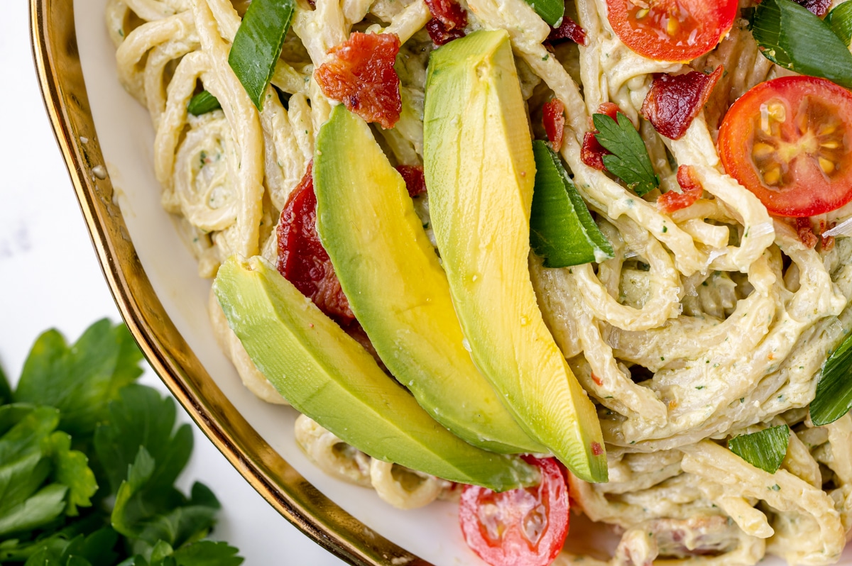 close up of avocado on plate of pasta