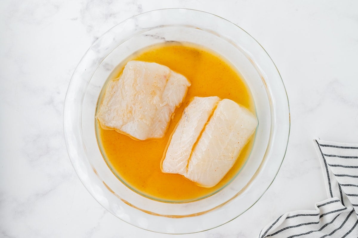 two pieces of fish marinating in a bowl