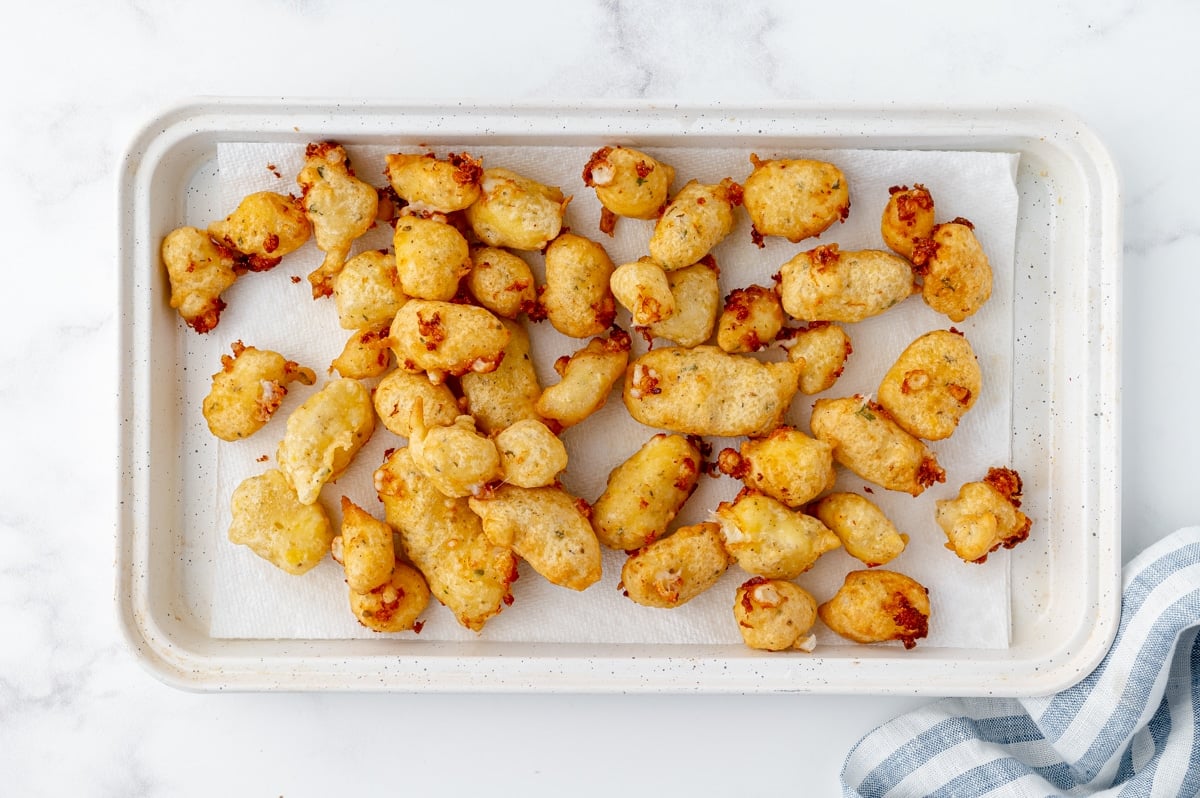 overhead shot of fried cheese curds on paper towel lined sheet pan
