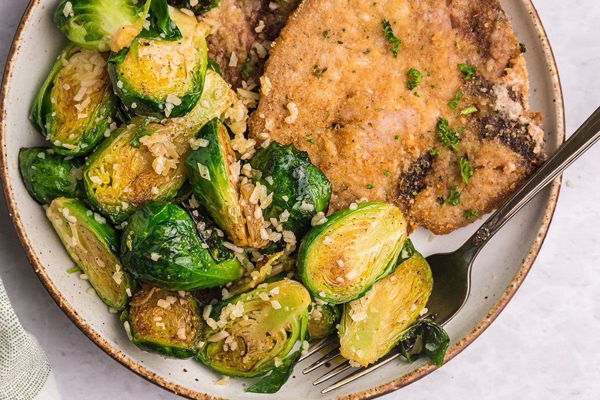 overhead shot of parmesan brussels sprouts on a plate with pork
