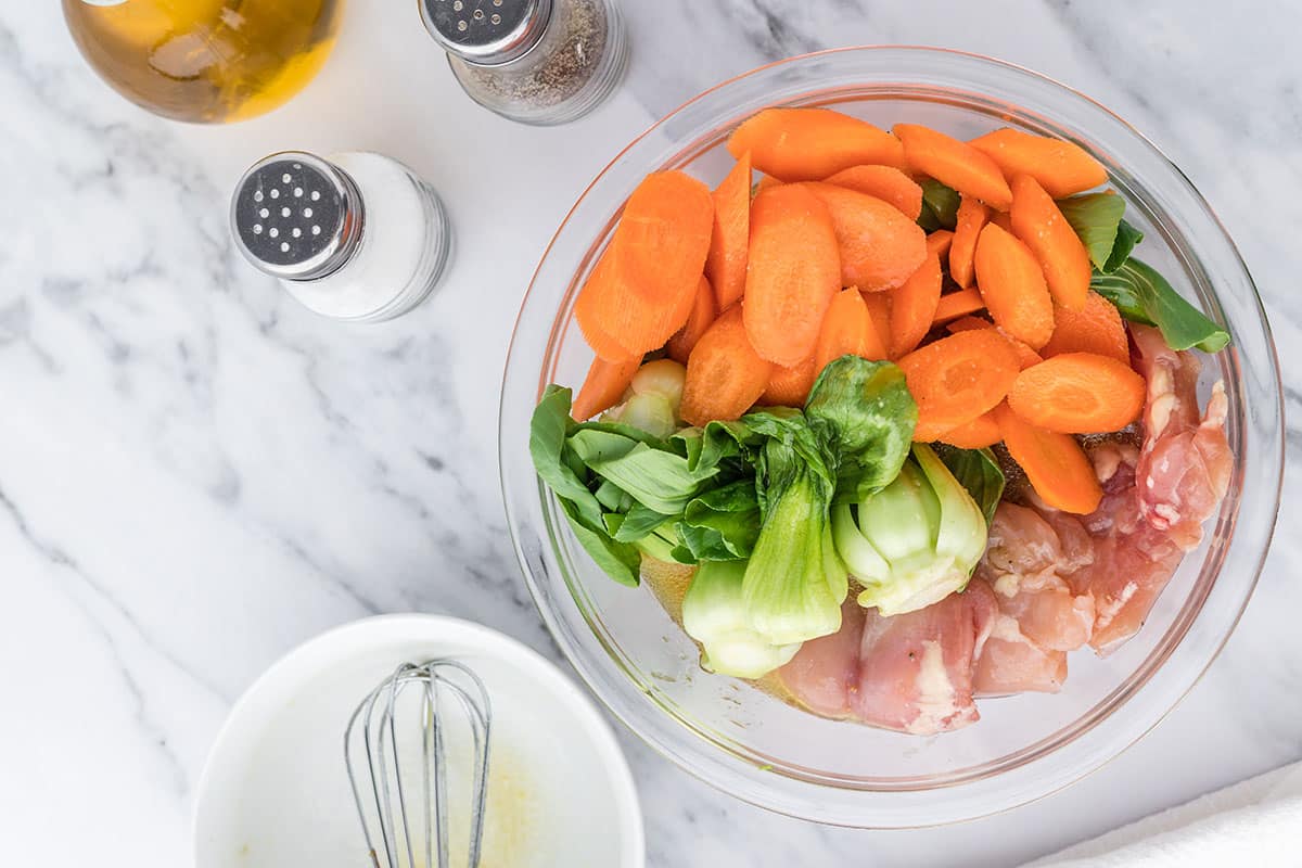 veggies and raw chicken in bowl with marinade