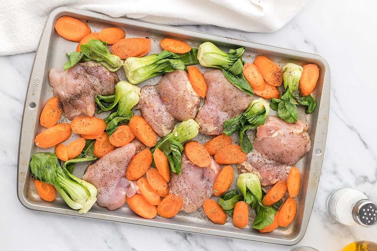raw chicken and veggies on sheet pan
