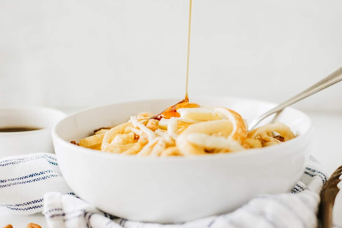 syrup poured onto bowl of pancake spaghetti