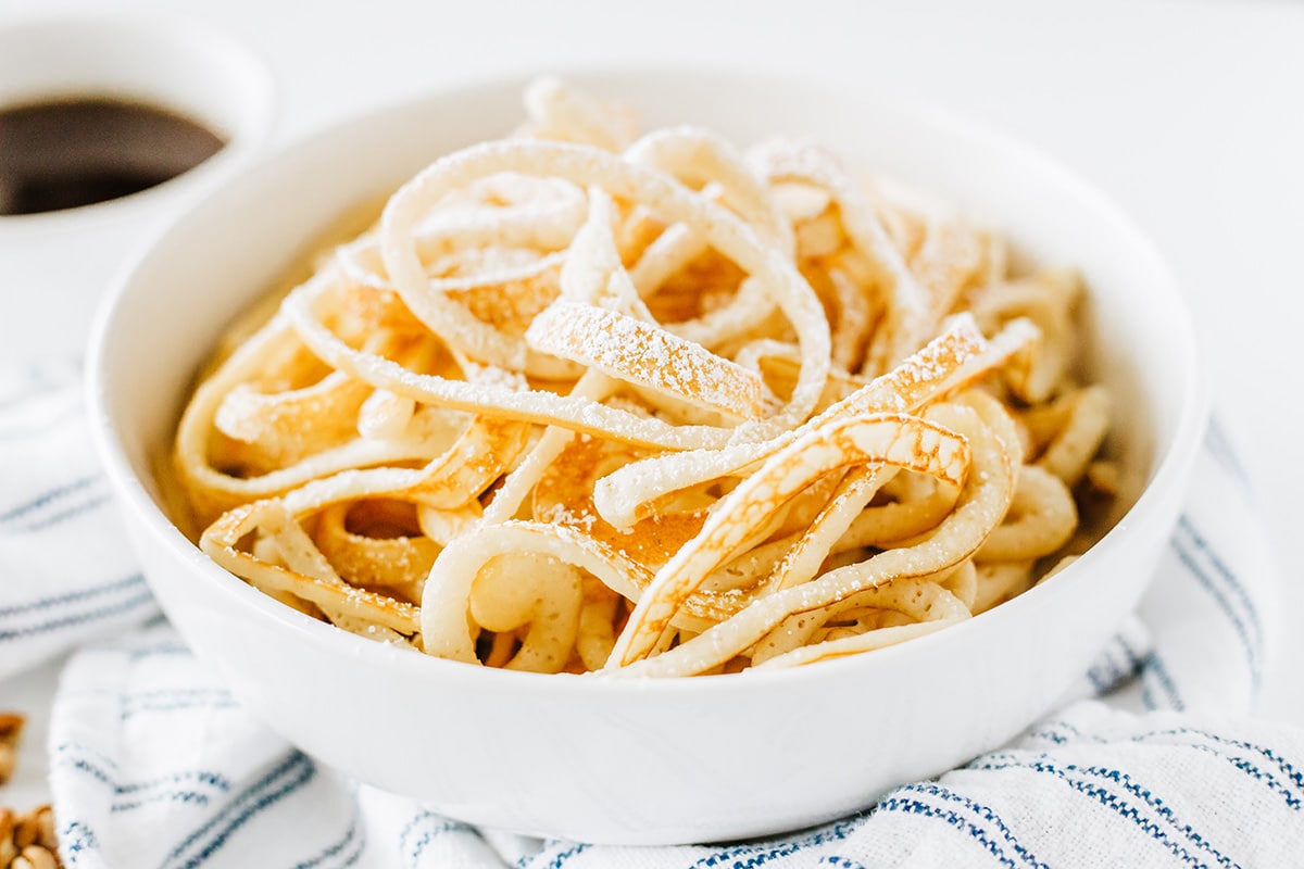 breakfast spaghetti in bowl topped with powdered sugar