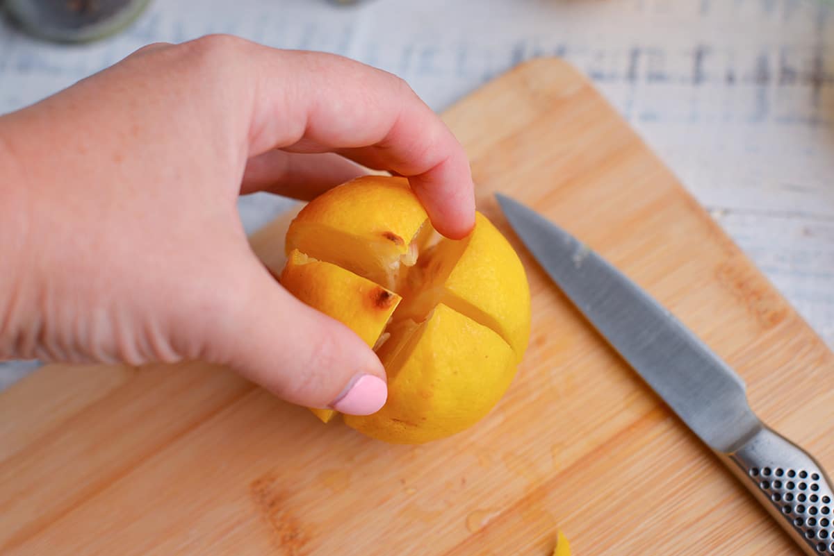 hand holding cut lemon on a cutting board
