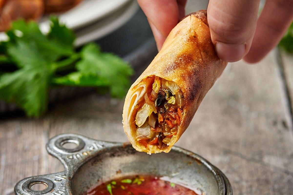 hand holding cut in half vegetable spring roll