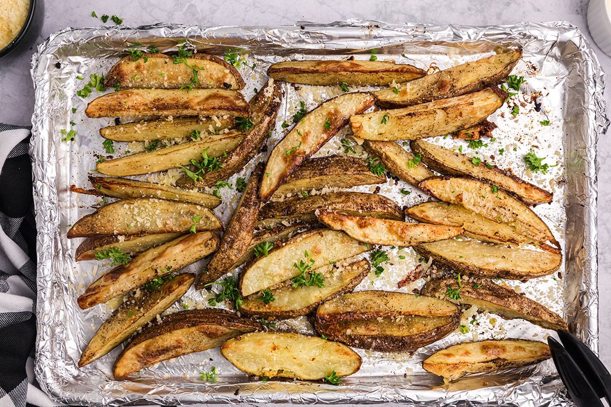 parsley sprinkled onto baked potato wedges on baking sheet