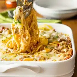 tongs tossing baked spaghetti casserole