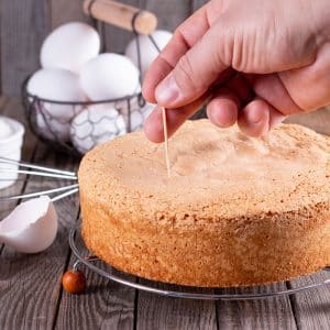 hand giving a toothpick test to a cake