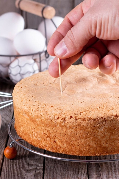 hand giving a toothpick test to a cake