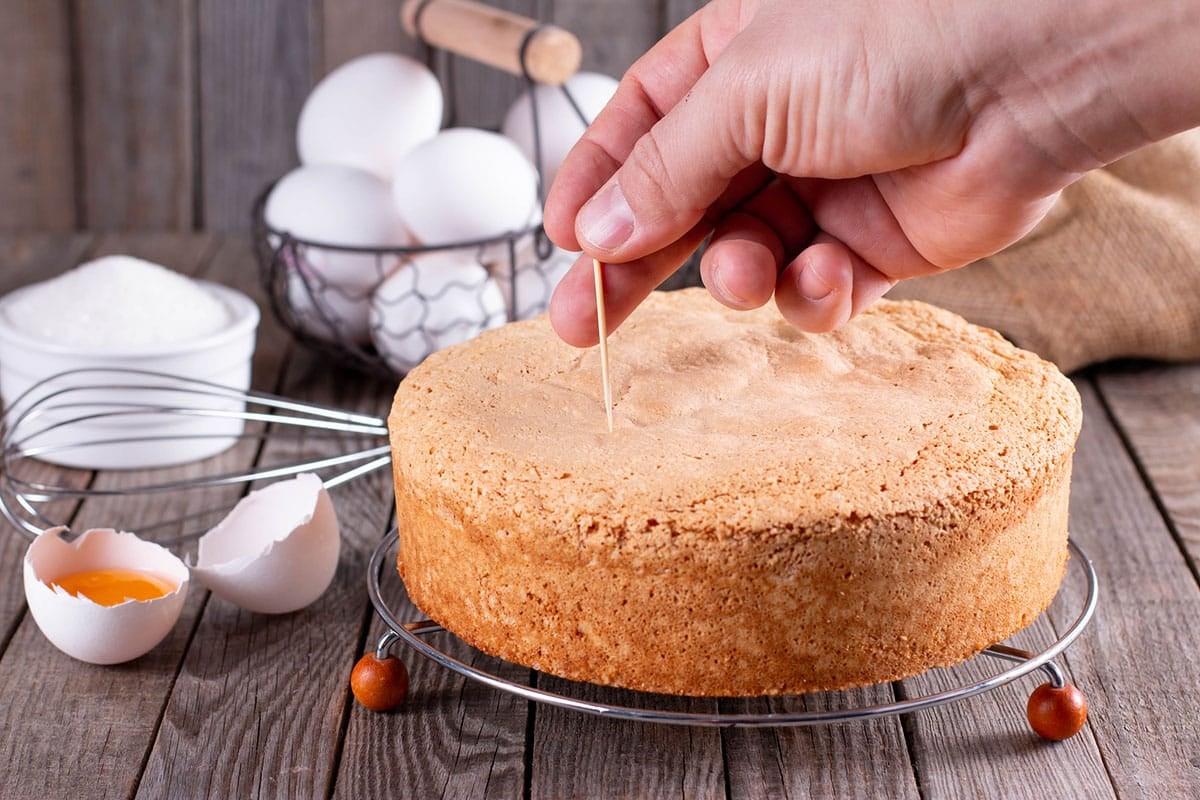 hand giving a toothpick test to a cake