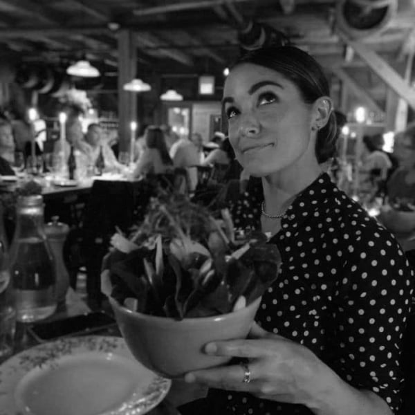 black and white image of woman looking up and holding bowl of food