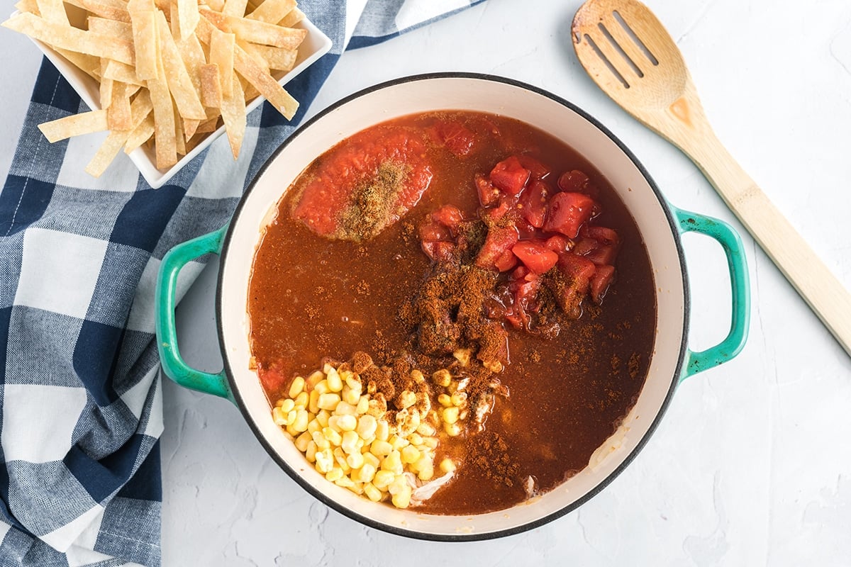 ingredients for chicken tortilla soup in a dutch oven to be made on the stove top