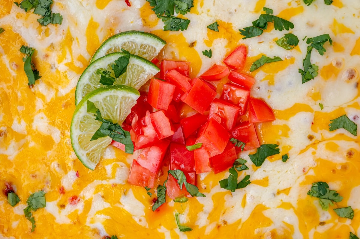 close up of diced tomatoes and lime on melted cheese