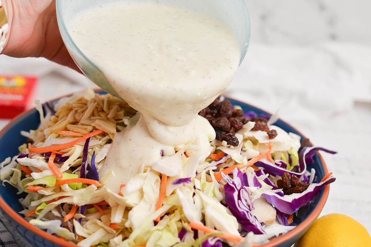 dressing poured into bowl of coleslaw ingredients