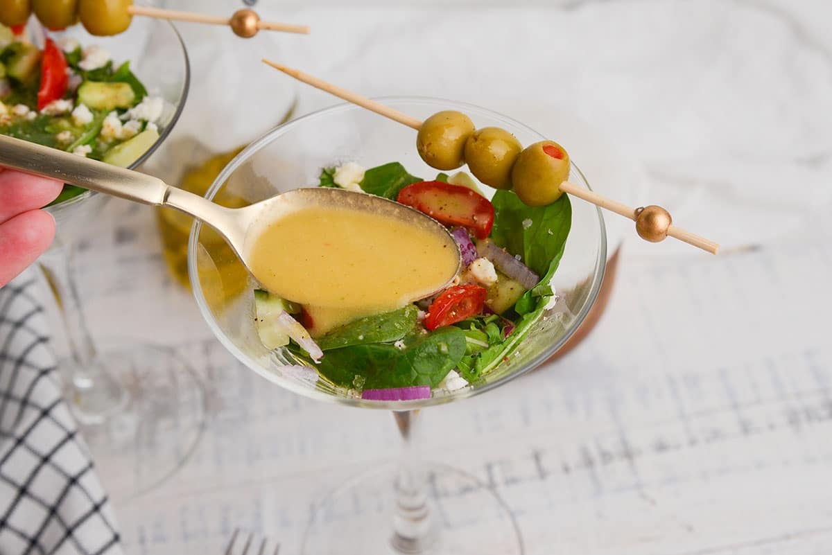 spooning dirty martini salad dressing onto salad