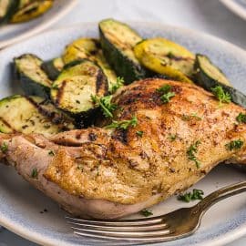 chicken thigh on plate with fork and veggies