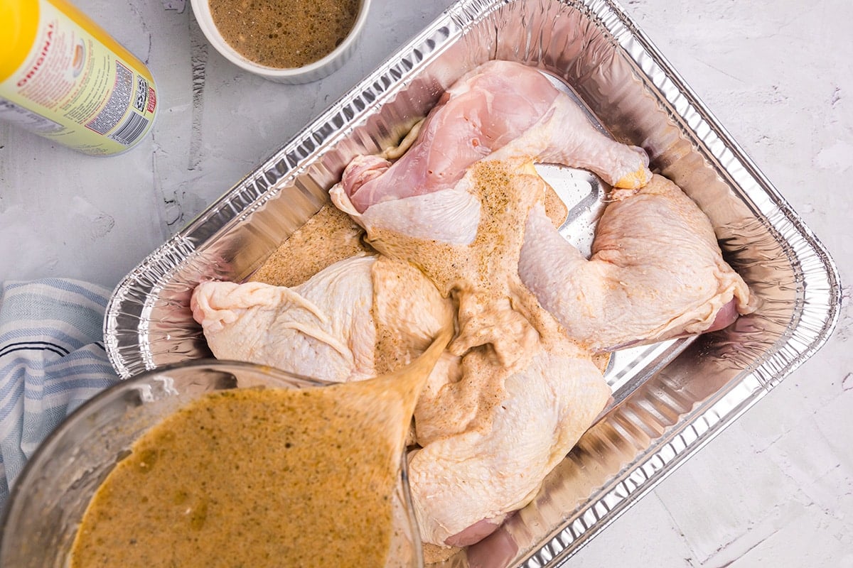 marinade poured over raw chicken in a foil pan
