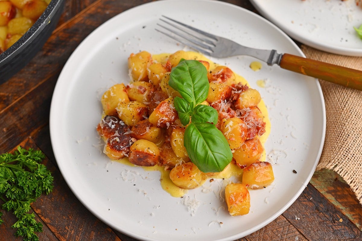 gnocchi carbonara on a white plate with basil