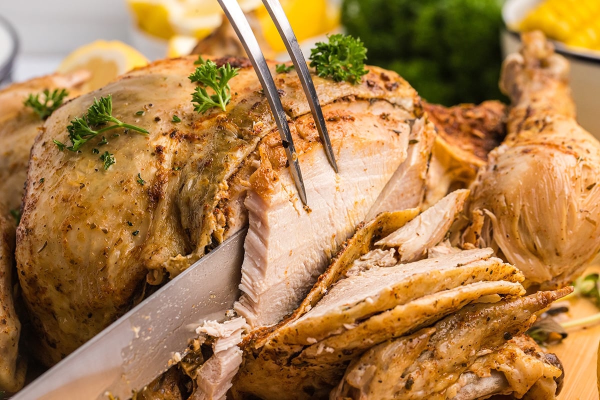 knife and fork slicing into whole chicken