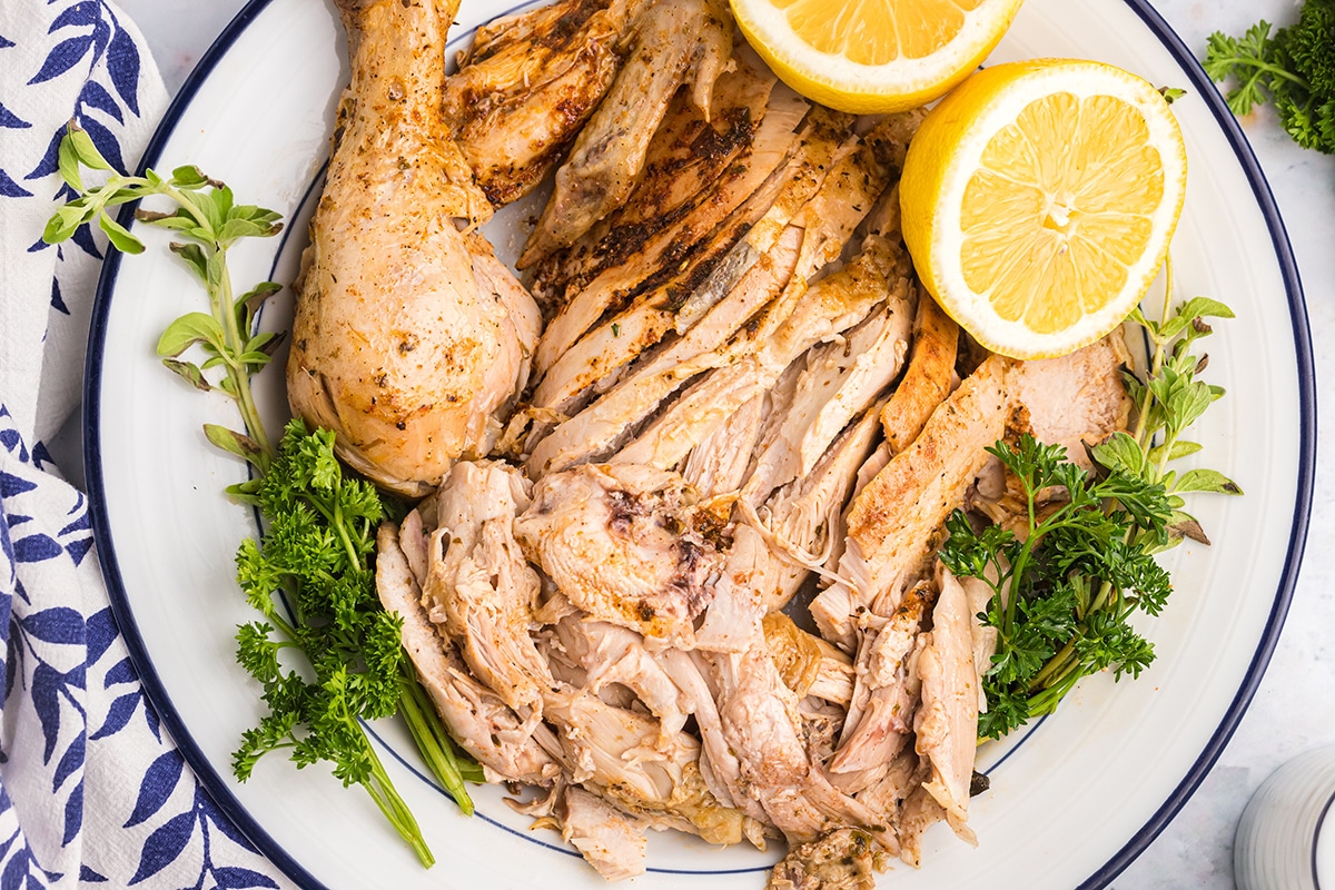 overhead shot of sliced instant pot whole chicken on a plate with lemon