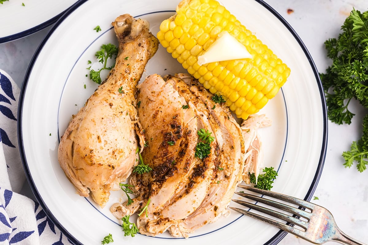 overhead shot of sliced chicken on a plate with corn on the cob