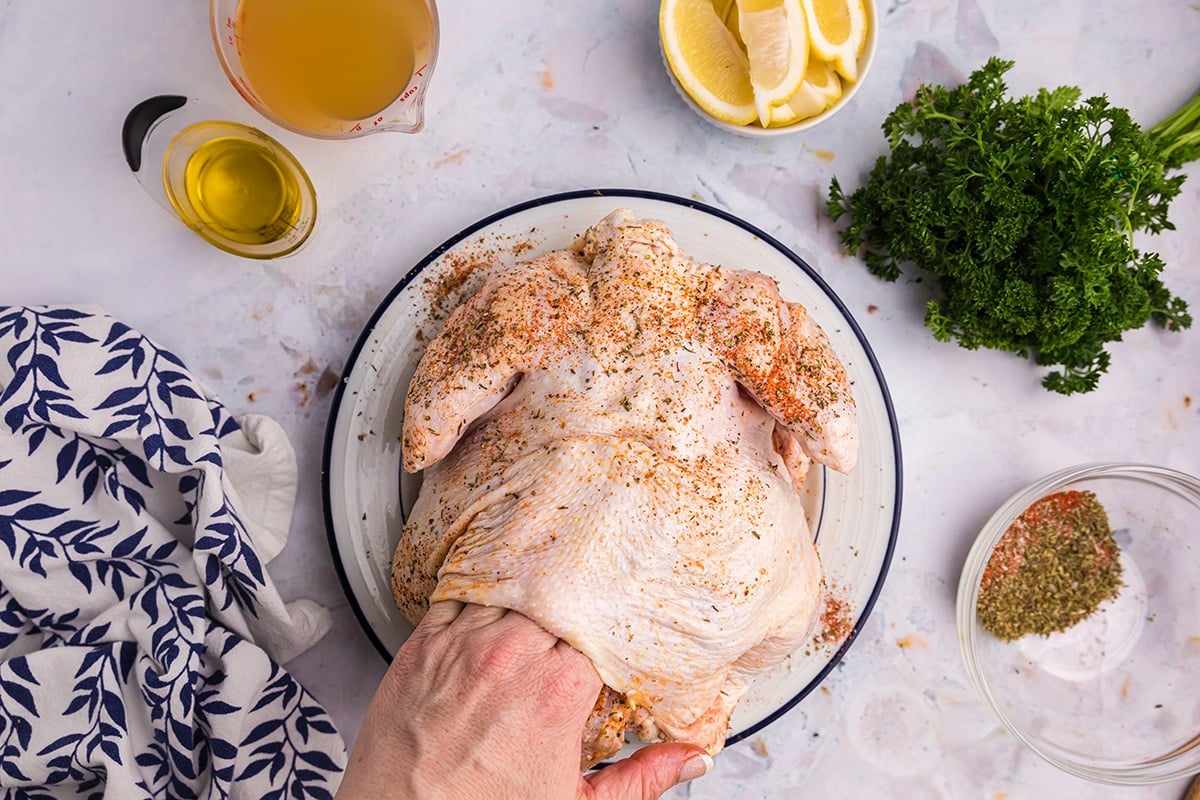 hand rubbing seasoning on chicken